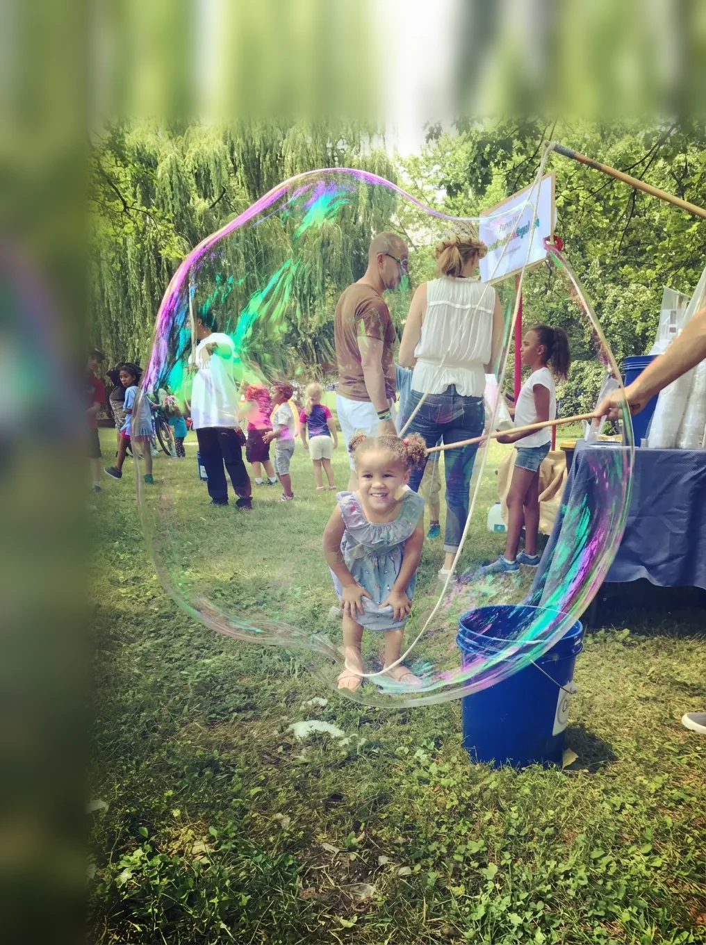 Young child smiling inside a giant iridescent bubble at a private birthday party in New York City