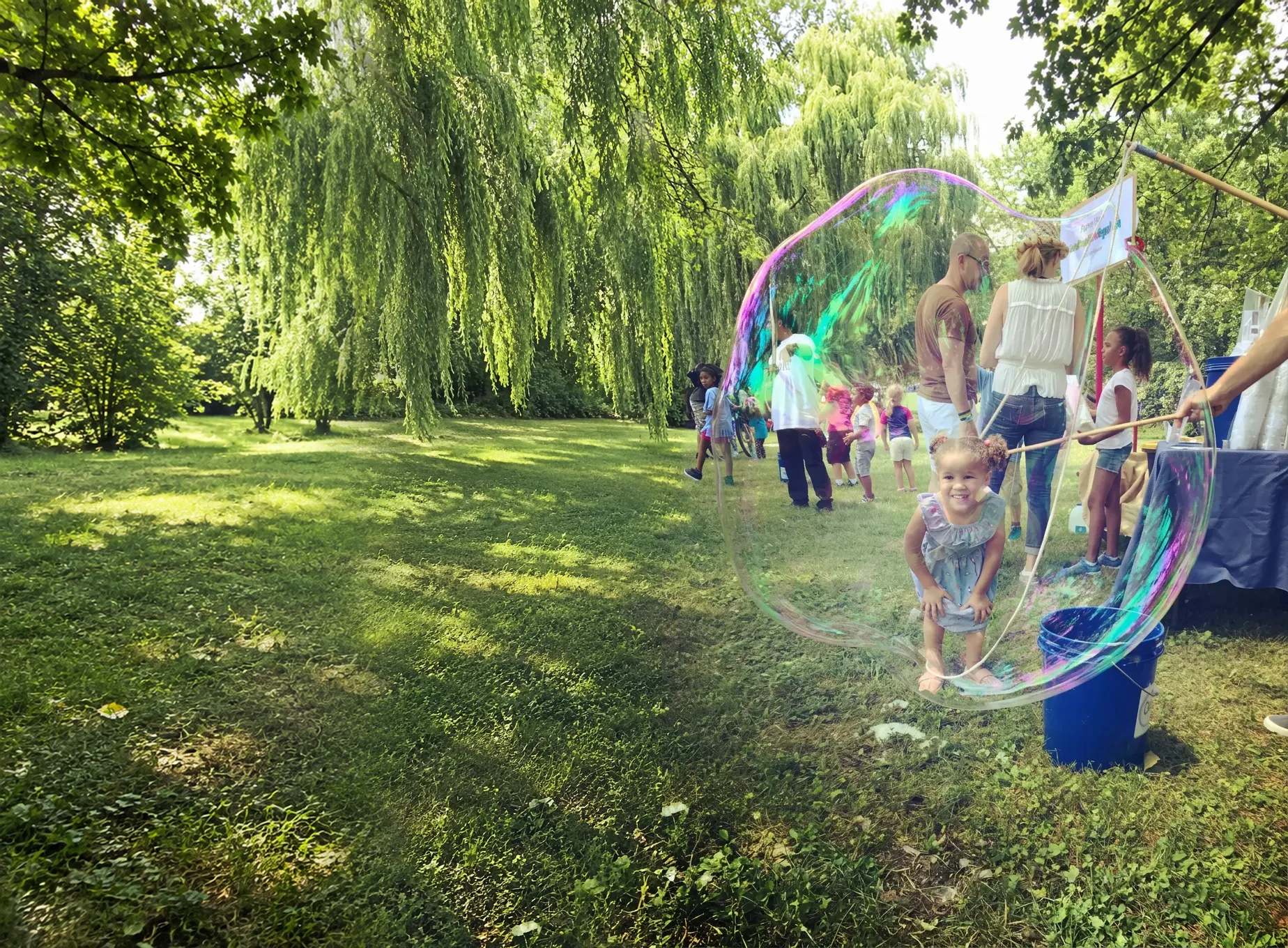 Smiling girl inside a giant bubble at a giant bubble party in a New York City park
